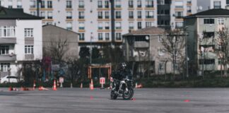 Motocyklista ćwiczący slalom między pachołkami na placu w mieście