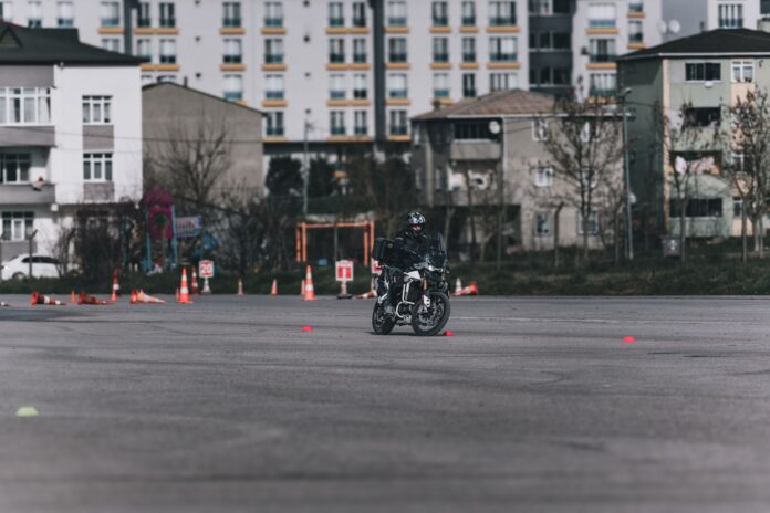 Motocyklista ćwiczący slalom między pachołkami na placu w mieście Motocyklista ćwiczący slalom między pachołkami na placu w mieście