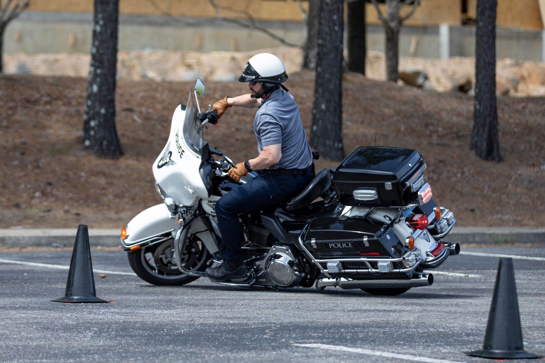 Policjant na motocyklu ćwiczy manewry między pachołkami na placu