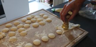 Przygotowywanie domowych ravioli nożem do makaronu na oprószonej mąką desce