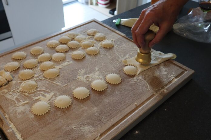 Przygotowywanie domowych ravioli nożem do makaronu na oprószonej mąką desce Przygotowywanie domowych ravioli nożem do makaronu na oprószonej mąką desce