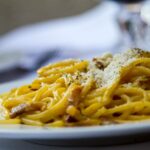 Planowanie włoskiego menu: techniki łączenia makaronu, sosu i dodatków Spaghetti carbonara z tartym parmezanem na białym talerzu