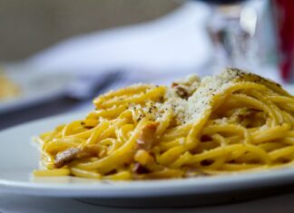 Planowanie włoskiego menu: techniki łączenia makaronu, sosu i dodatków Spaghetti carbonara z tartym parmezanem na białym talerzu