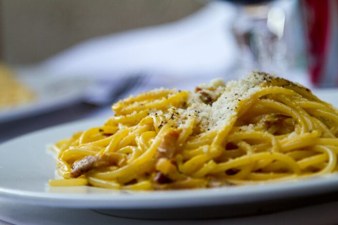 Spaghetti carbonara z tartym parmezanem na białym talerzu Spaghetti carbonara z tartym parmezanem na białym talerzu