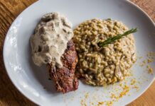 Stek z sosem podany z kremowym risotto grzybowym na talerzu