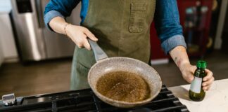 Szef kuchni trzyma patelnię z oliwą do smażenia w kuchni