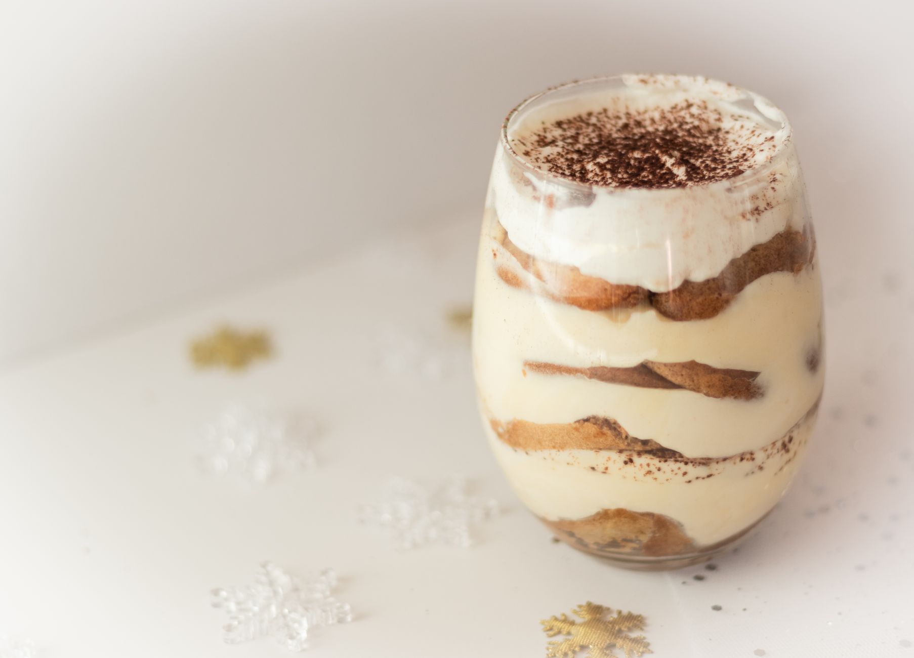 Zbliżenie na kremowe tiramisu w szklance z posypką z kakao